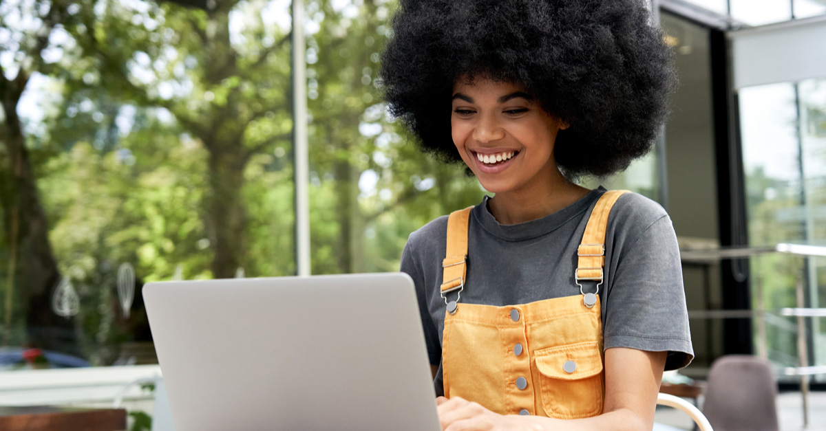 Black female Screenwriter working on a beat sheet on her laptop outdoors