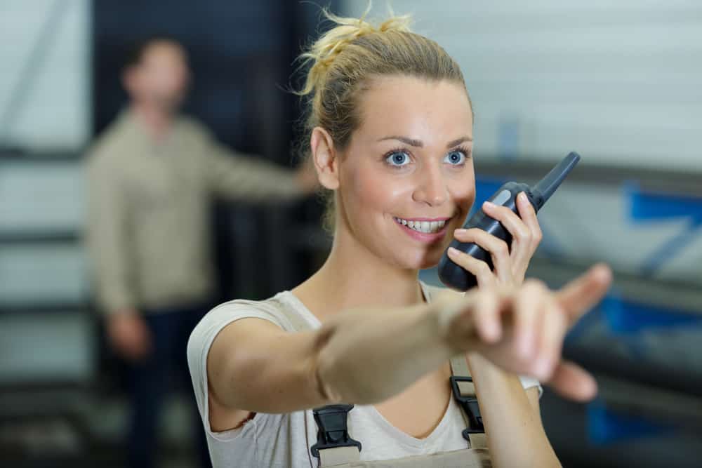 Female Key PA talking into walkie talkie on set