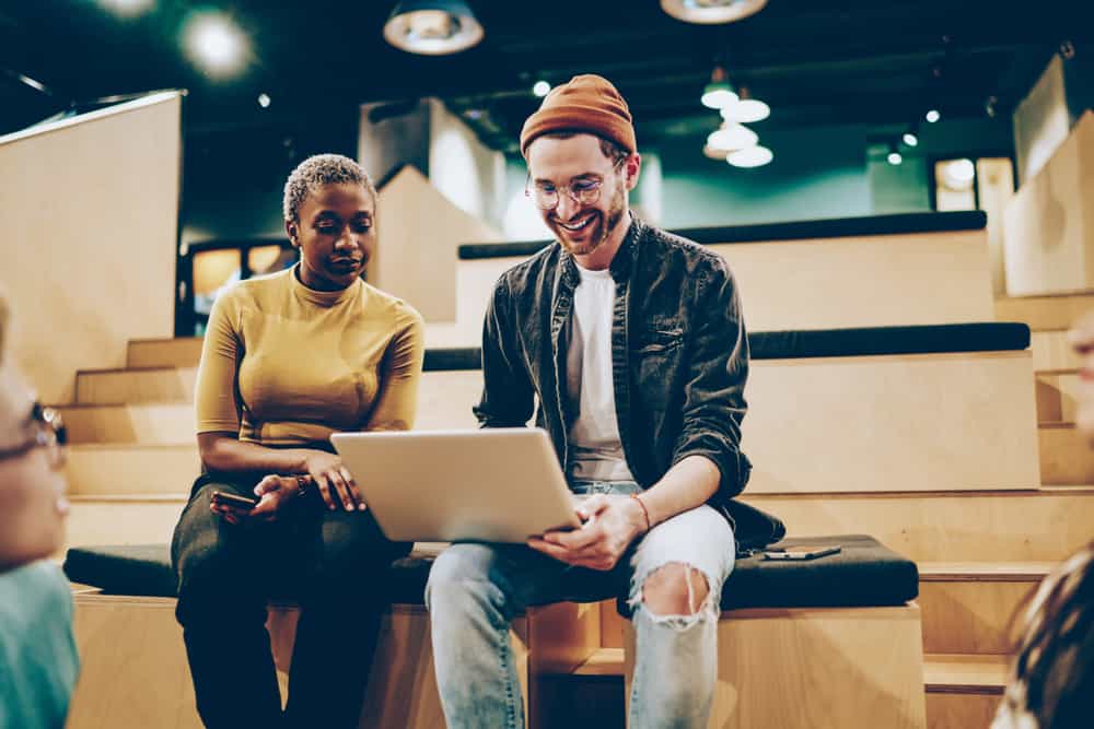 Male and female screenwriting duo looking at a laptop