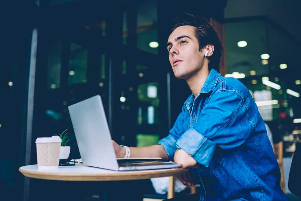 Young man at cafe writing a script on his laptop